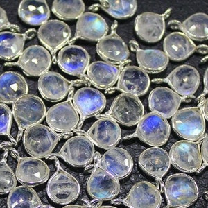 May include: A pile of iridescent white moonstone teardrop pendants with silver bail loops. The stones have a rainbow sheen.