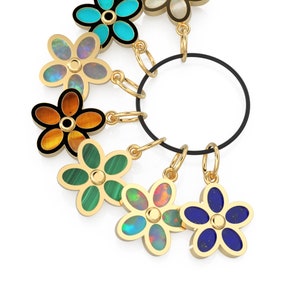 May include: A set of seven gold flower charms with different colored gemstones, hanging from a black cord.