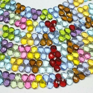 May include: A strand of faceted gemstone beads in various colors, including clear, blue, green, yellow, pink, and red. The beads are round and have a slightly irregular shape.
