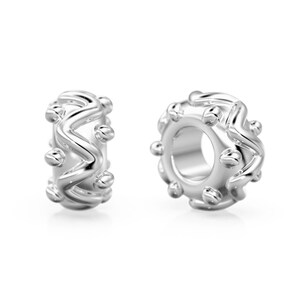May include: Two silver charm spacers with a wavy design and small beads around the edge.