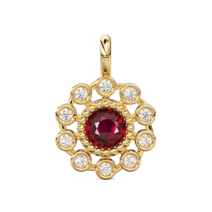 Pode incluir: Pingente de ouro com uma pedra preciosa vermelha escura redonda no centro, rodeada por um halo de pedras preciosas claras menores. O pingente tem um design vazado e uma argola na parte superior para uma corrente.