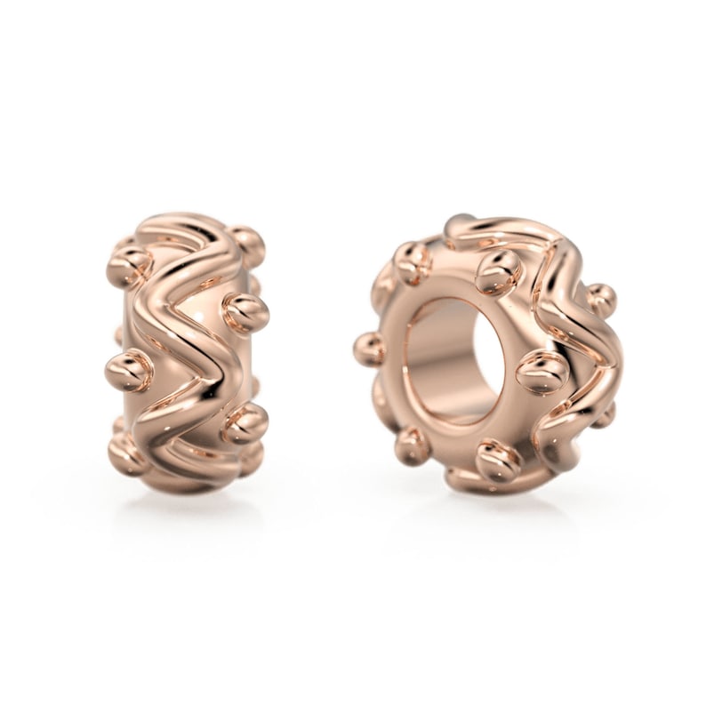 May include: Two rose gold charm beads with a wavy, textured design and small round accents.