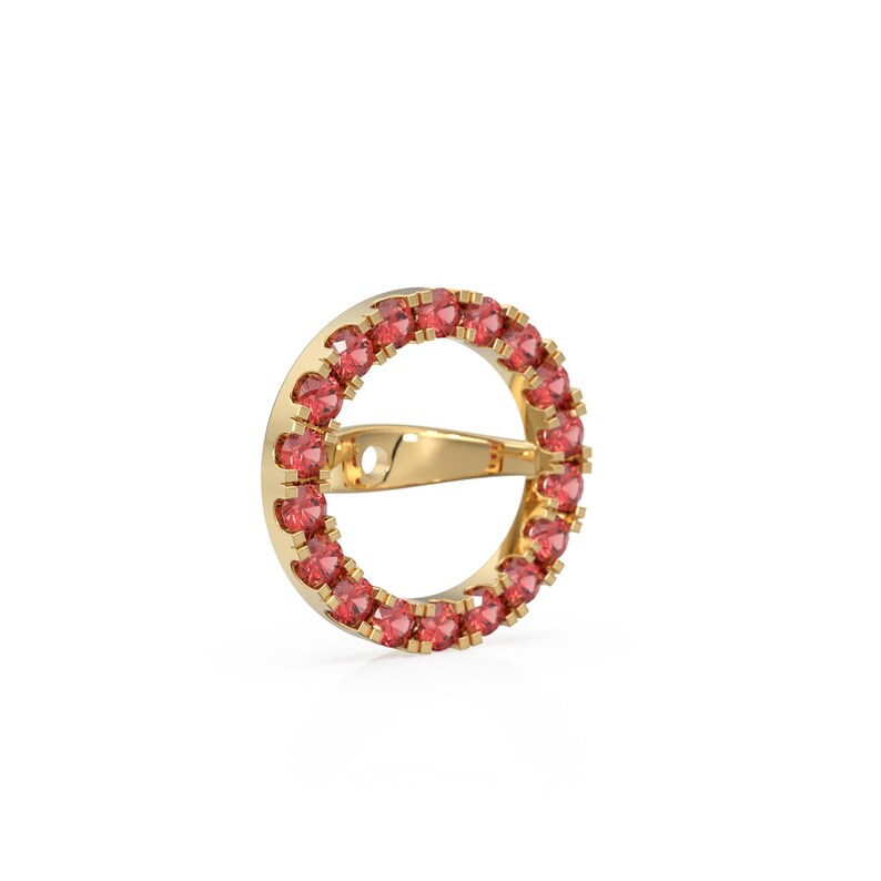 May include: A gold earring featuring a circular design. The earring is embellished with small, round, red gemstones set around the outer edge. It has a post and clasp for secure wear.