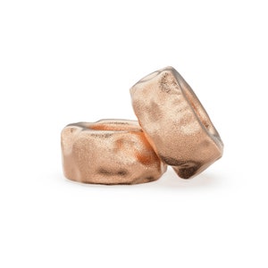 May include: Two gold-colored metal rings with a textured surface.