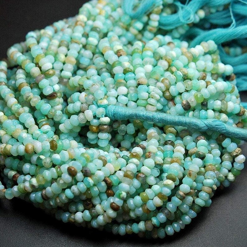 May include: A strand of turquoise blue opal beads, faceted and polished, with a slight variation in colour and size. The beads are strung on a turquoise blue thread.