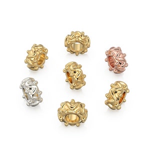 May include: Six gold, silver, and rose gold charm beads with a wavy design. The beads are all the same size and shape, and they are arranged in a circle.