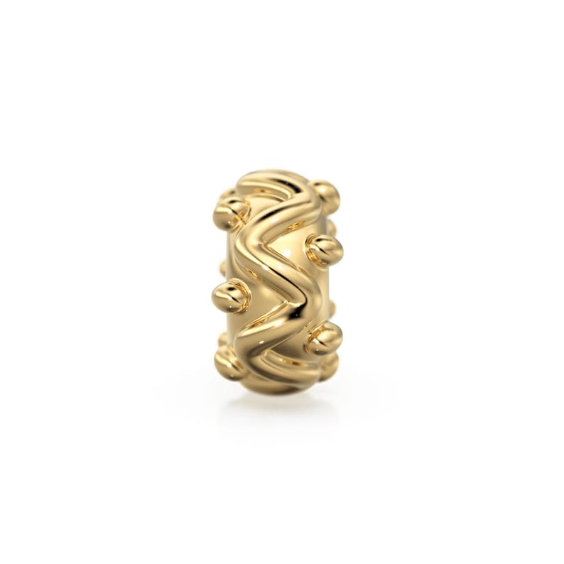 May include: A gold-colored ring with a textured, wavy design and small round accents.