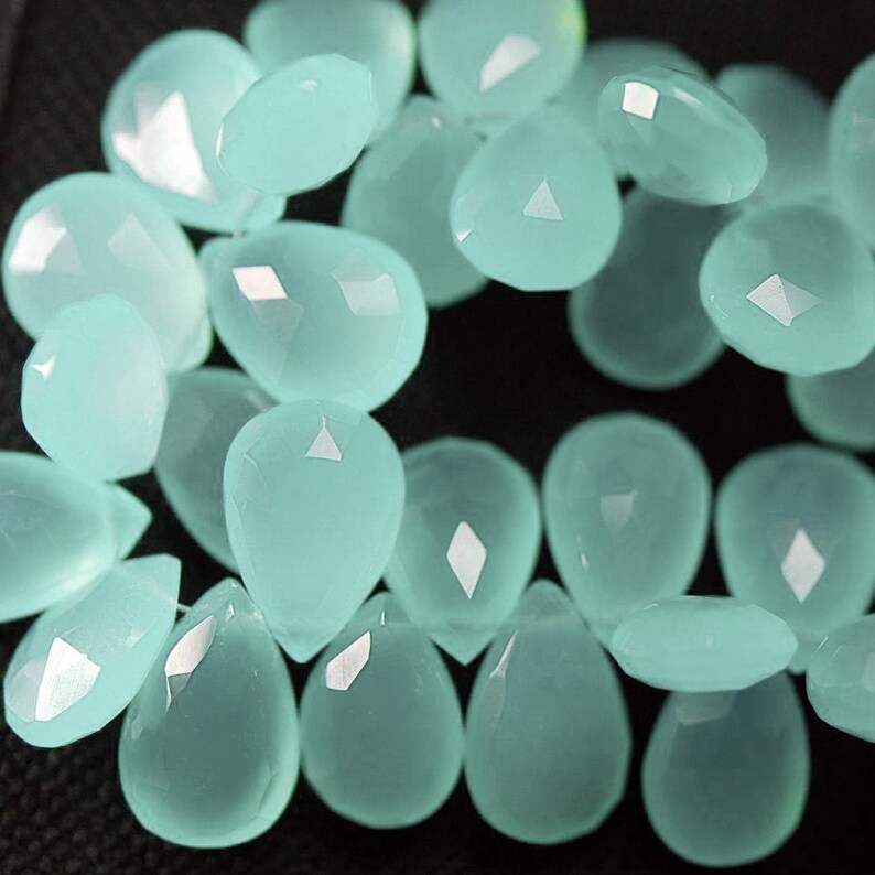 May include: A strand of light blue gemstone beads, each bead is faceted and shaped like a teardrop.
