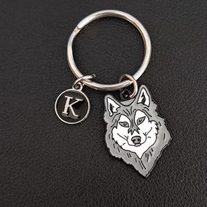 May include: A silver key chain with a black and white wolf charm and a black charm with the letter K.