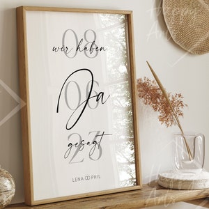 Könnte beinhalten: Ein gerahmter Druck mit weißem Hintergrund und schwarzem Text. Der Text lautet "08 wir haben Ja gesagt 23 LENA & PHIL". Der Druck hängt an einem Holzregal.