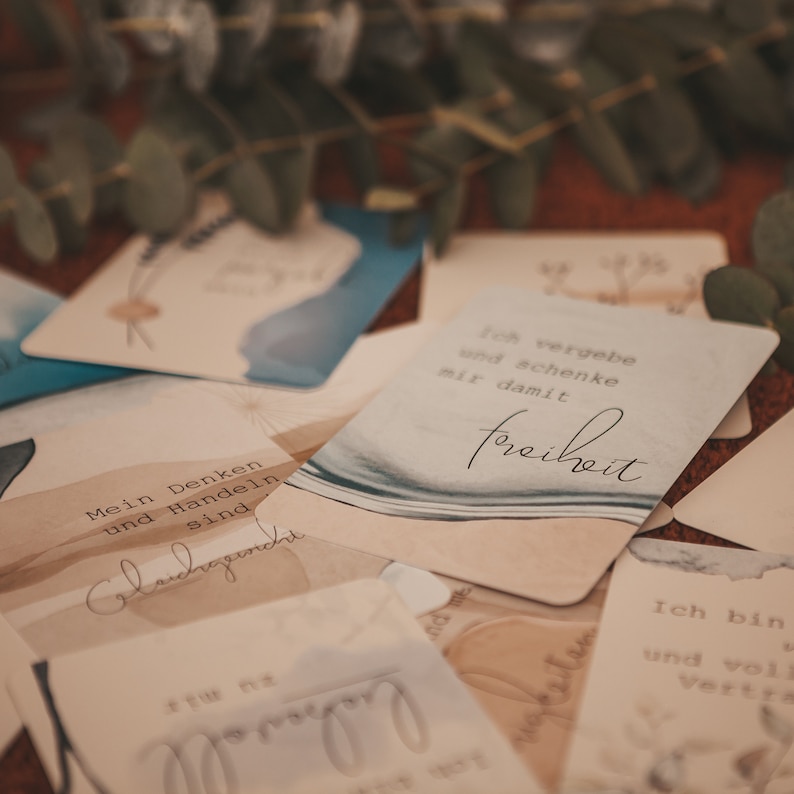 May include: A set of affirmation cards with watercolor backgrounds. The cards feature phrases in German, including "Mein Denken und Handeln sind" and "Ich vergebe und schenke mir damit Freiheit".