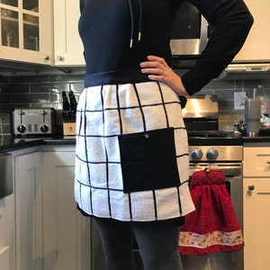 May include: A white and black checkered kitchen apron with a black pocket. The apron is made of a soft, absorbent material and is perfect for protecting your clothes while you cook.