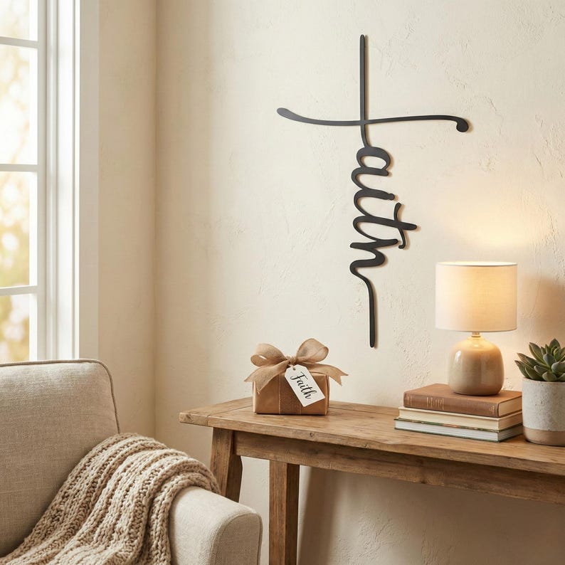 a cozy living room corner with a wooden console table, a lamp, a stack of books, and a small gift box with a bow. Above the console table, there is a metal cross-shaped sign with the word "Faith" written on it.
