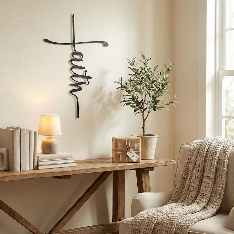 a cozy living room with a wooden console table, a lamp, a small potted plant, and a beige blanket draped over the back of a chair. A large metal sign with the word "Faith" written on it is hanging on the wall above the console table.
