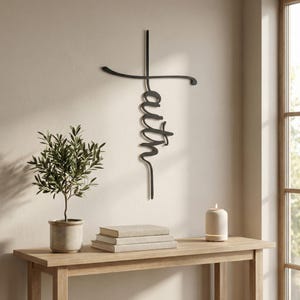 a wooden console table with a potted plant, a stack of books, and a candle on it. Above the table, there is a metal cross-shaped decoration with the word "Faith" written on it.