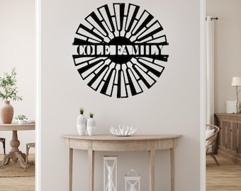 May include: A black metal windmill wall art piece with the text "COLE FAMILY" in the center. The windmill design is circular with radiating blades. The artwork is mounted on a white wall above a wooden console table.