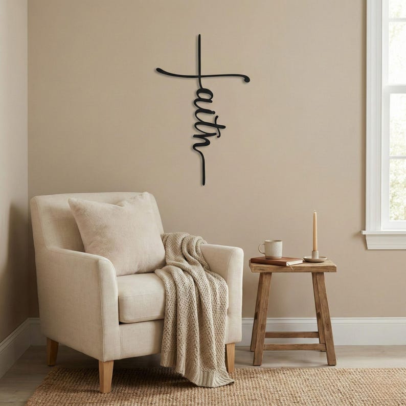 a cozy living room with a beige armchair, a wooden side table, and a candle on the table. Above the armchair, there is a decorative metal cross with the word "Faith" written on it.
