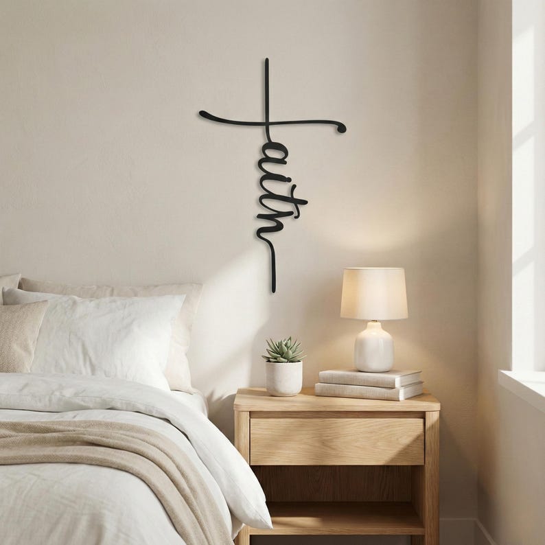 A bedroom with a bed, nightstand, and lamp, along with a cross-shaped sign that says "Faith" hanging on the wall.