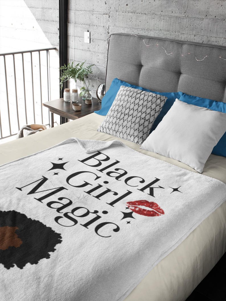 May include: White throw blanket with the text "Black Girl Magic" in black script, a red lipstick kiss mark, and black star accents. The blanket features a black and brown afro graphic.