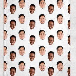 May include: White blanket featuring a repeating pattern of smiling faces. The faces are of diverse individuals, with varying skin tones and hairstyles. The blanket is a soft, cozy home textile.