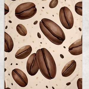 May include: A beige blanket with a repeating pattern of large, brown coffee beans and smaller coffee bean accents. The coffee beans are detailed with light and dark brown shading, creating a watercolor effect.
