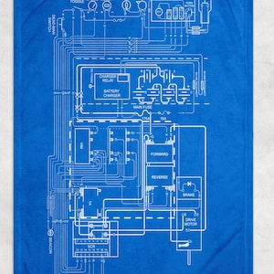 May include: A blue blanket featuring a detailed white schematic diagram of an electrical system. The diagram includes labels such as "Fuel Hour Gauge Meter," "Battery Charger," and "Drive Motor." The blanket is rectangular and appears to be made of soft material.