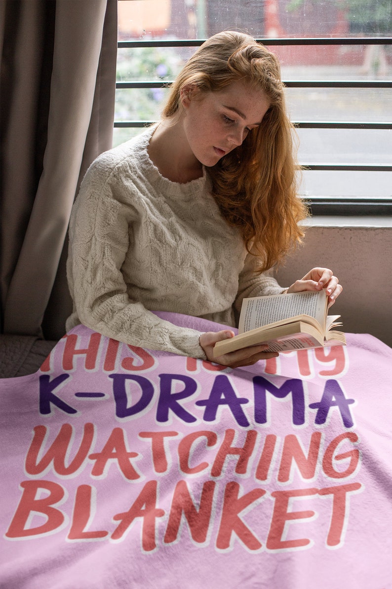 May include: A pink fleece blanket with the text "This is my K-Drama watching blanket" in purple, pink, and orange lettering.