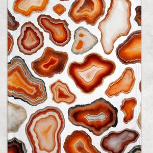 May include: A white blanket featuring a repeating pattern of agate slices in shades of orange, brown, and cream. The agate designs vary in size and shape, creating a natural, organic aesthetic. The blanket is a cozy home decor item.