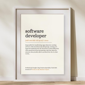 Peut inclure: Une affiche encadrée présentant une définition de type dictionnaire pour software developer. Le texte inclut la prononciation phonétique, la classification en tant que nom et une description humoristique du rôle, finissant par des titres en orange.