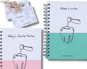 May include: Two spiral bound notebooks with a dental theme. The covers are split in half, with one half white and the other half a solid colour. The top half of each notebook features a black and white illustration of a tooth with a dental drill. The bottom half of the notebook on the left is pink and the bottom half of the notebook on the right is teal. The text on the notebooks reads "Abby's Dental Notes" and "Adam's notes". The text "FONT 4" is printed below the notebooks.