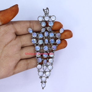May include: A silver pendant with a teardrop shape, featuring a cluster of round moonstone and diamond gemstones. The pendant is set in a delicate, intricate design.
