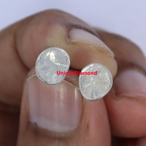 May include: A pair of silver stud earrings featuring rough, white, natural diamonds. The diamonds are set in a silver bezel setting. The earrings are a unique and elegant way to add a touch of sparkle to any outfit.