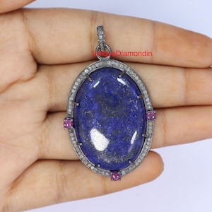 May include: Oval pendant featuring a large blue lapis lazuli gemstone surrounded by a halo of small diamonds. The pendant is accented with four small pink gemstones.