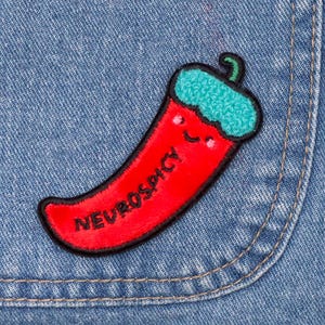 Peut inclure: Patch brodé en forme de piment rouge avec un visage souriant et le texte "NEUROSPICY" sur un fond en jean bleu.