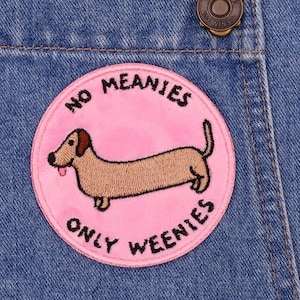 May include: A pink and white embroidered patch with a dachshund and the text "No Meanies Only Weenies".