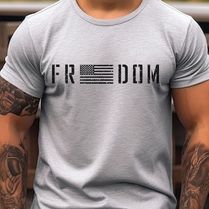 May include: A gray t-shirt with a black print of the word "FREEDOM" with an American flag in place of the "O".