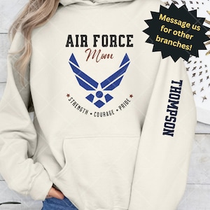 May include: A cream-colored hoodie with a blue Air Force logo and the text "AIR FORCE Mom *STRENGTH COURAGE PRIDE*" on the front. The text "THOMPSON" is on the left sleeve.
