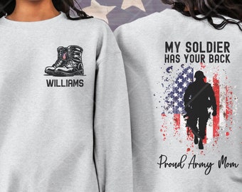 May include: Gray sweatshirt with the text "My Soldier Has Your Back" and an American flag graphic. The sweatshirt also has the text "Proud Army Mom" and a silhouette of a soldier. The other side of the sweatshirt has a pair of military boots and the text "Williams".