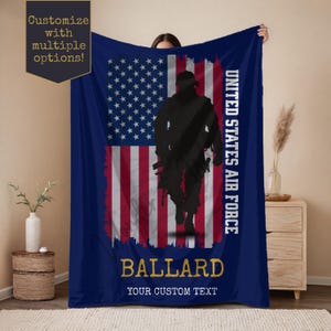 May include: A navy blue blanket featuring the American flag with a distressed design. A black silhouette of a soldier is superimposed over the flag. The words "UNITED STATES AIR FORCE", "BALLARD", and "YOUR CUSTOM TEXT" are also displayed.