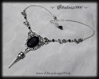May include: A silver necklace featuring a black gemstone pendant, a skull charm, and black beads. The pendant is surrounded by a silver filigree design with roses. The necklace is displayed against a white background.