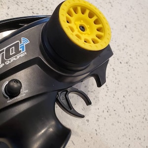 May include: Black remote control with a yellow and black tire wheel on top. The remote control has a trigger and a dial labeled "multifunction". The text "Top Qualifier" is printed on the remote control.