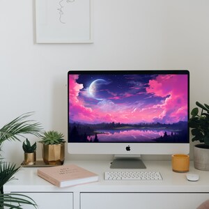 K&ouml;nnte beinhalten: Ein wei&szlig;er Desktop-Computer mit einer rosa und violetten Landschafts-Tapete, die einen Halbmond und Sterne zeigt. Der Computer steht auf einem wei&szlig;en Schreibtisch mit einer Tastatur, einem Buch und einer Topfpflanze.