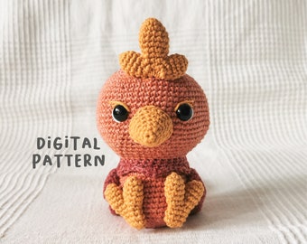 May include: A crocheted amigurumi bird toy with a red-brown body, orange beak, and black eyes. The bird is sitting on a white surface.  The text "DIGITAL PATTERN" is visible in the image.