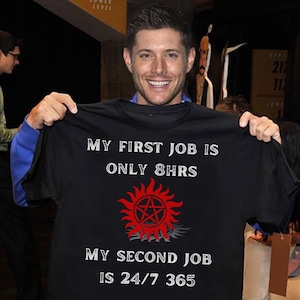 May include: Black t-shirt with white text that reads "My first job is only 8hrs. My second job is 24/7 365". A red and black symbol is centered on the shirt.