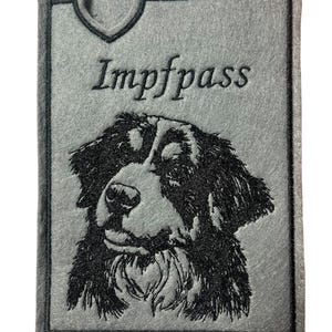 Könnte beinhalten: Grauer Filz-Impfausweis-Halter mit schwarzem, gesticktem Bild eines Berner Sennenhundes. Der Text "Impfpass" ist über dem Kopf des Hundes gestickt.