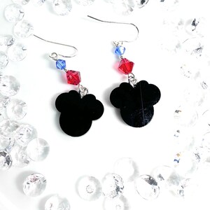May include: A pair of silver dangle earrings with black Mickey Mouse head charms. Each earring features a red and blue crystal bead.