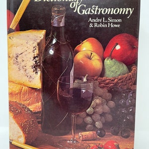 May include: A book titled "Dictionary of Gastronomy" by Andre L. Simon & Robin Howe. The cover features a still life of a bottle of wine, a glass of wine, cheese, bread, grapes, apples, pears, and strawberries.