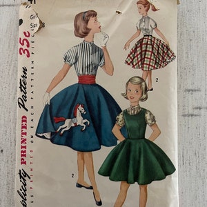 May include: Vintage Simplicity sewing pattern for a girl's dress. The pattern is for a 35 cent, one-piece dress. The pattern shows three different styles of dresses, one with a plaid skirt, one with a solid green skirt, and one with a blue skirt with a white horse applique. The pattern is labeled "Simplicity Printed Pattern".