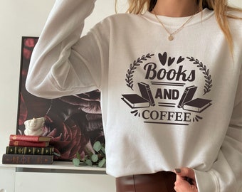 May include: White sweatshirt with a brown graphic design that says "Books and Coffee" with a wreath and two books on either side of the text.