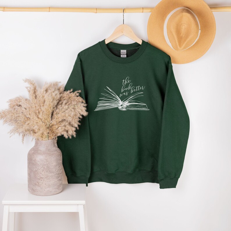May include: A dark green sweatshirt with a white graphic of an open book and the text "the book was better".